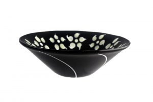 Black fused glass bowl with white flowers on inner rim and curved white stripe on outer sides